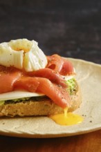 A breakfast dish features sliced smoked salmon and a poached egg on top of toasted bread. Liquid