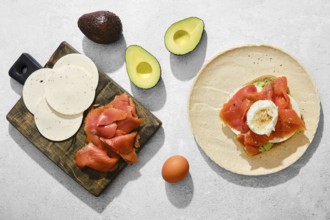 Top view of ingredients for smoked salmon sandwich with avocado, goat cheese and poached egg on a