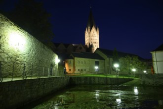 A Gothic church illuminated at night with illuminated tower and dark sky in the foreground the