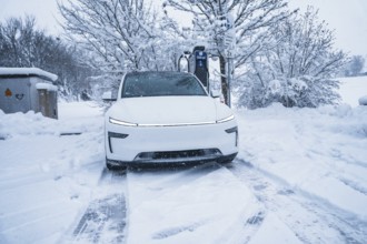 Electric car charging at a charging station in a snowy winter landscape, Tesla Model Y electric