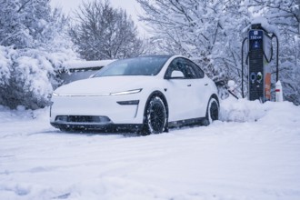 Electric car in a snowy area stands next to a charging station, Tesla Model Y electric car, ENBW