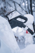 Close-up of a charging cable connected to a car in a snowy environment, Tesla Model Y electric car,