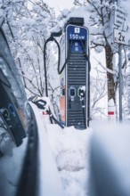 150 kW charging station in snowy surroundings next to an electric car, Tesla Model Y electric car,