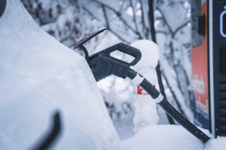 Close-up of a charging cable connected to an electric car in snowy surroundings, Tesla Model Y