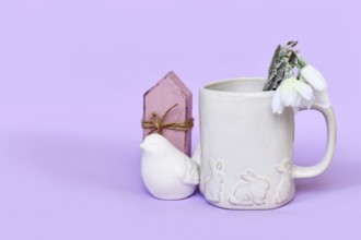 Cute spring decor arrangement with bird, tulip flowers and mug with Easter bunnies, bird and