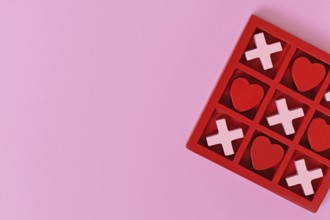 Valentine-themed heart game with red and pink hearts and Xs in a red box on a pink background with