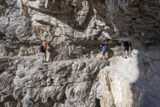Mountaineers on an exposed rock band in the secured via ferrata Bocciere Centrale, Brenta