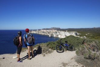 Cyclists look at the ville haute or upper town or medieval old town of Bonifacio, Corse-du-Sud