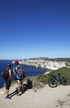 Cyclists look at the ville haute or upper town or medieval old town of Bonifacio, Corse-du-Sud