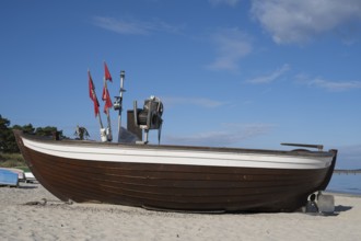 Boat with fishing flags lying on sandy beach, blue sky, Binz, seaside resort, Rügen island, Baltic
