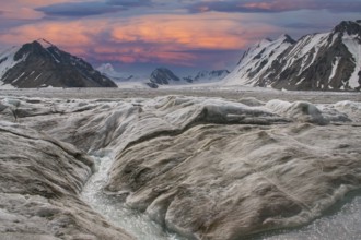 Glaciers with meltwater at sunset against an impressive, snow-covered mountain backdrop in Altai