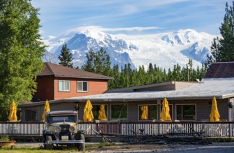 Vintage car and historic building in front of mountain landscape with Kennicott Glacier, McCarthy,