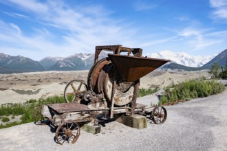Old rusted moving mill for rock in front of mountain landscape with Kennicott Glacier, Historic