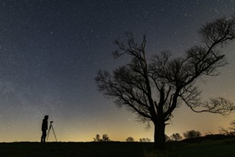 Photographer in front of a tree on the Hunte dyke in Ochsenmoor am Dümmer at night with stars,