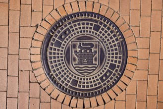 Manhole cover, city coat of arms, paving brick footpath, sunny, Eckernförde, Rendsburg-Eckernförde