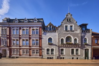 Historic residential buildings, façade with windows, gables and tail gables, paving street, blue