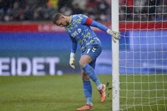 Goalkeeper Marvin Schwäbe 1. FC Koeln KOE (01) knocks clay off the post, snow, snow drift, winter,