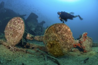 Underwater photo of diver swimming over Boonsung wreck looking at parts of former sunken tin