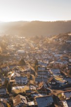 View of a village in winter at sunrise with snow-covered roofs and a golden atmosphere, Glatten,