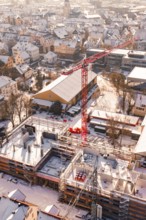 Snowy town with a construction site and a distinctive red crane, Zellerschule building, Nagold,