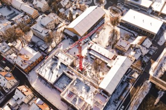 Bird's eye view of snow-covered city with construction crane and surrounding buildings in warm