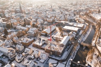 City in winter with an active construction site and visible church roof in the background,