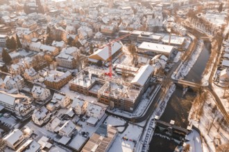 Snowy town with red construction crane standing on a construction site near a river, Zellerschule