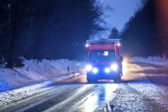 Ambulance during an alarm trip, with flashing lights, in winter, slush, slippery roads, country