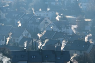 Cold winter morning view of a settlement with numerous smoking chimneys, symbolic image,