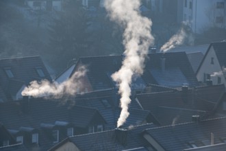 Snowy roofs and smoking chimneys under blue morning light in the city, symbolic image, fireplaces,