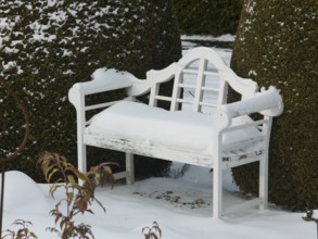 White snow upholstery on the white garden bench, East Frisia, Germany