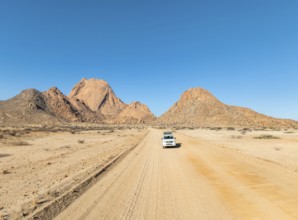 Car on sandy road, mountains in the desert, Spitzkoppe summit, Namib desert, Namibia