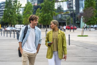 Diverse business colleagues walking outdoors through a modern city park, having an engaging