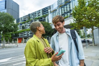 Two diverse colleagues enjoying a casual conversation and sharing a smartphone screen on an urban