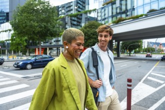 Two diverse colleagues smiling and walking together on a city street, representing collaboration,