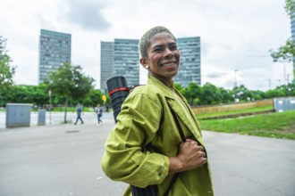 Smiling woman architect carrying a drawing tube on her shoulder. Walking confidently through a