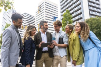 Diverse business professionals smiling and communicating, looking at a digital tablet together on a