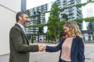 Two business colleagues exchanging a handshake in a modern city environment, symbolizing a