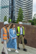 Construction professionals walking and discussing a project on a city street, wearing hard hats and