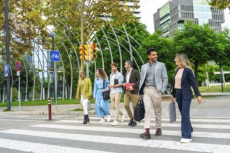 Diverse group of smiling business people walking across a street crosswalk in a modern city