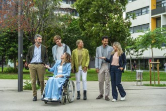 Diverse group of business people, including a woman in a wheelchair, engaging in a lively outdoor