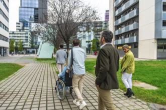 Diverse group of colleagues walking on a paved pathway through a modern city district, one person