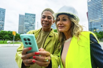 Diverse women architects and engineers smiling and collaborating outdoors in a modern city, using a