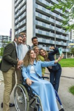 Group of multi ethnic colleagues and friends, including a woman in a wheelchair, smiling and taking