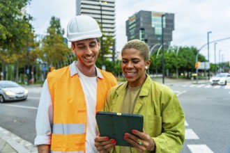 Construction manager man in hard hat and woman architect reviewing building plans on a digital