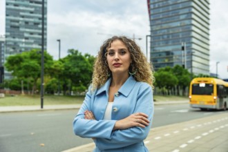 Young professional businesswoman with curly hair standing confidently with crossed arms on an urban