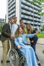 Diverse group of smiling colleagues with a woman in a wheelchair taking a cheerful selfie together