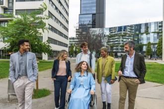 Diverse group of smiling business people, including a woman in a wheelchair, actively collaborating