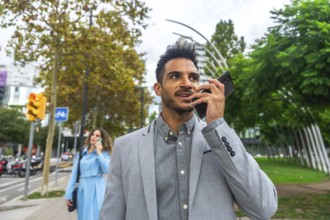 Confident young business professional communicating on a mobile phone, using its speaker function