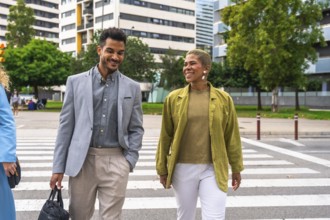 Two diverse business colleagues crossing a city street while engaging in a friendly conversation,